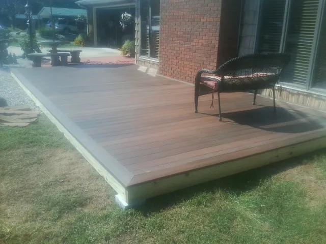 New wood deck and wicker chair beside a brick house in Carson